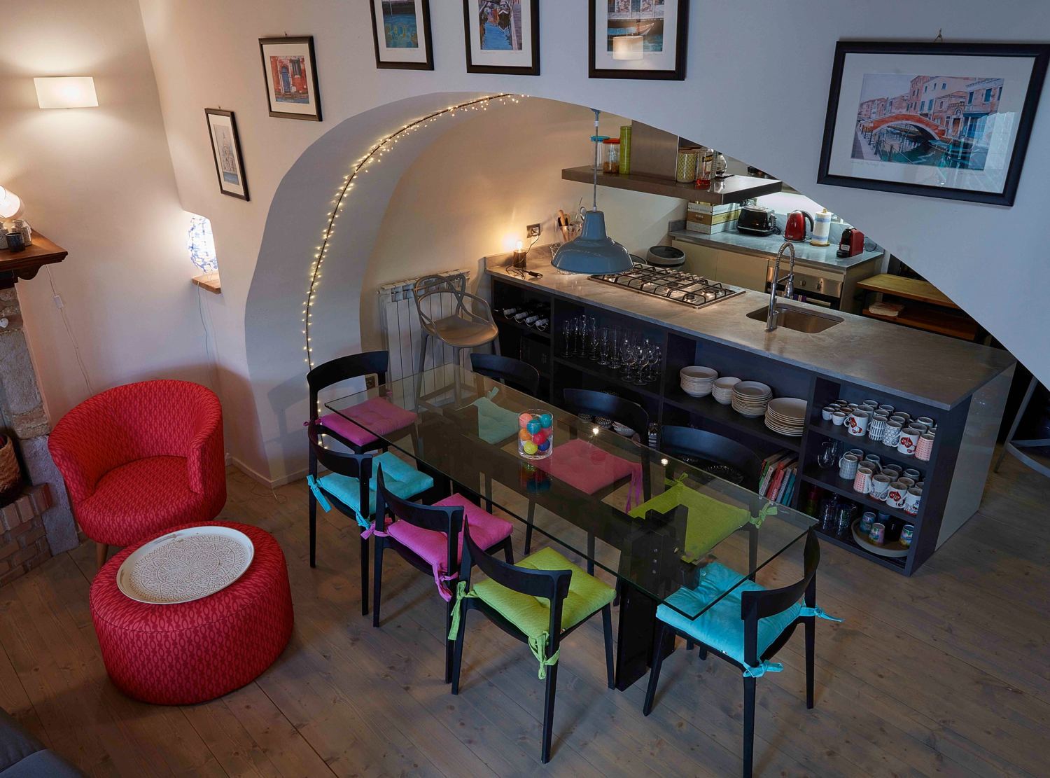 Dining table with eight coloured chairs beside the open kitchen