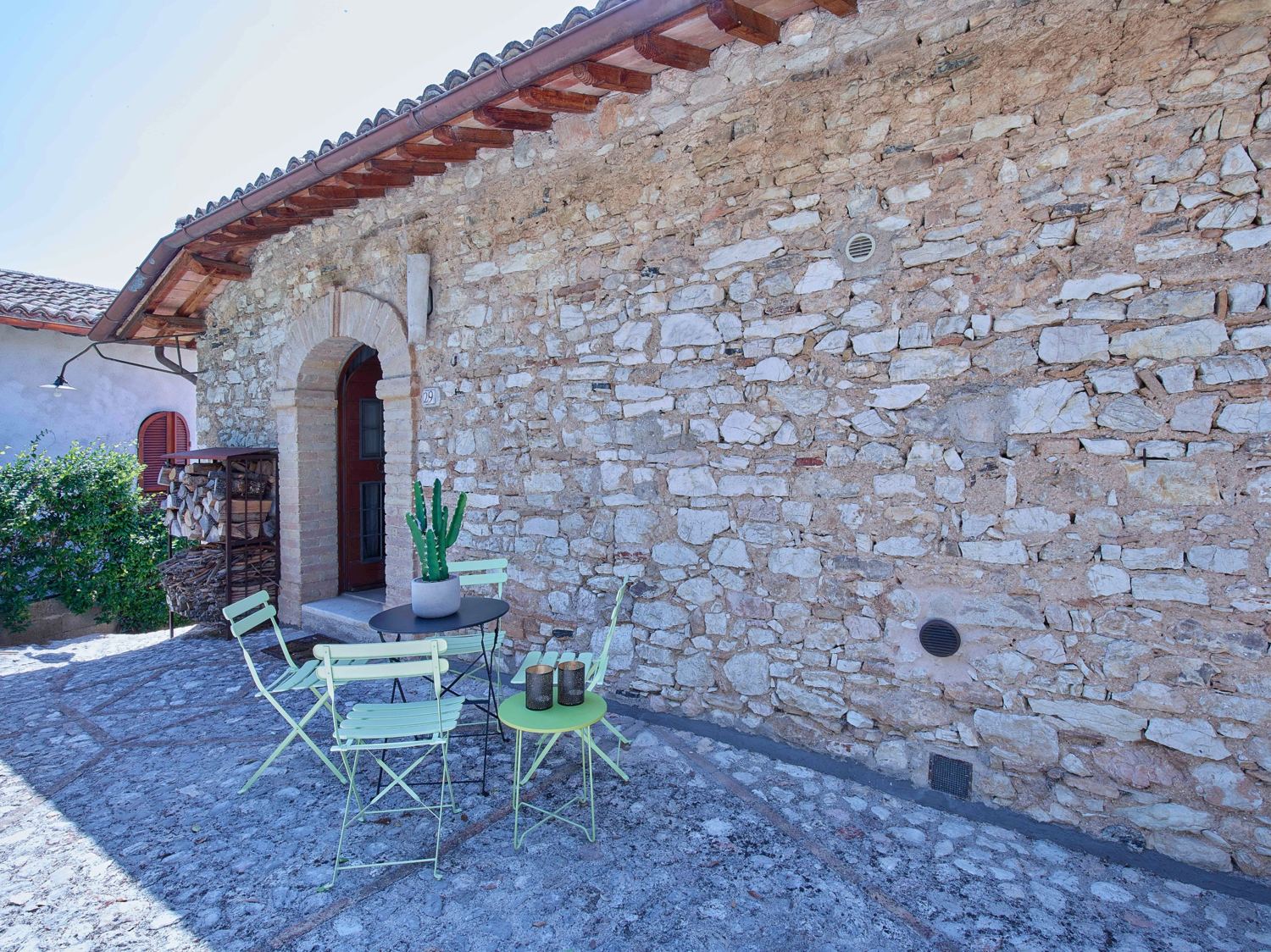 The stone front of the house with its arched door and courtyard table