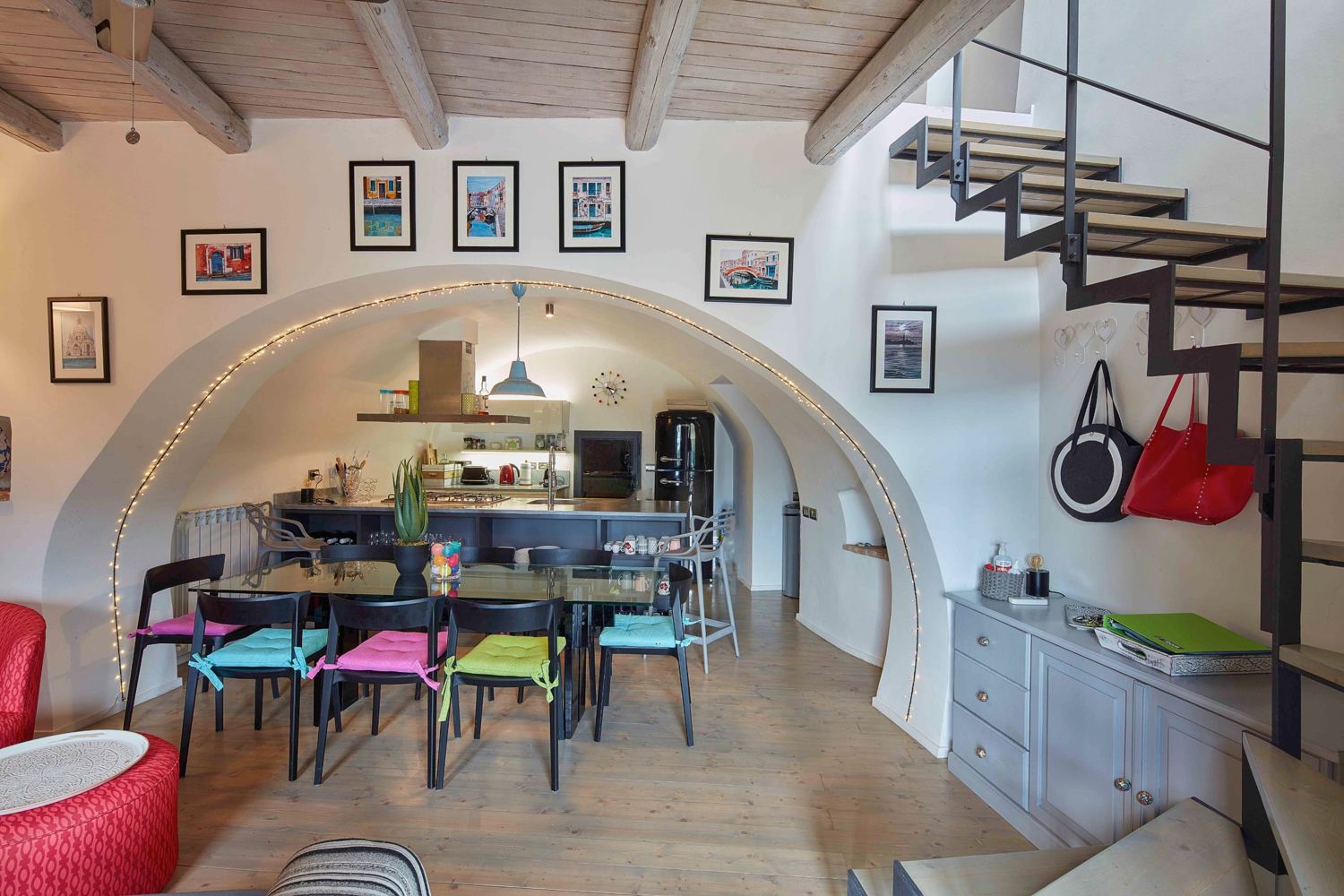 Kitchen under a white arch with the staircase to the upper floor
