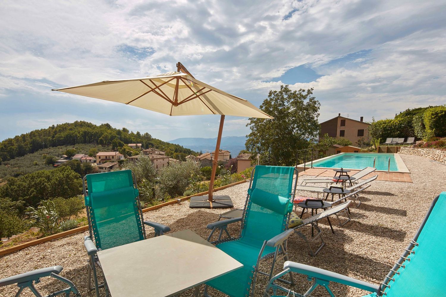 Loungers and a parasol beside the pool, with the village behind
