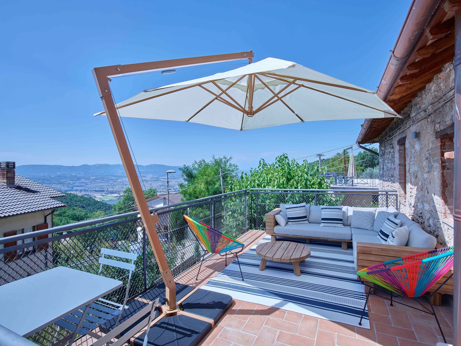 Roof terrace with a parasol, corner sofa and a view across the valley