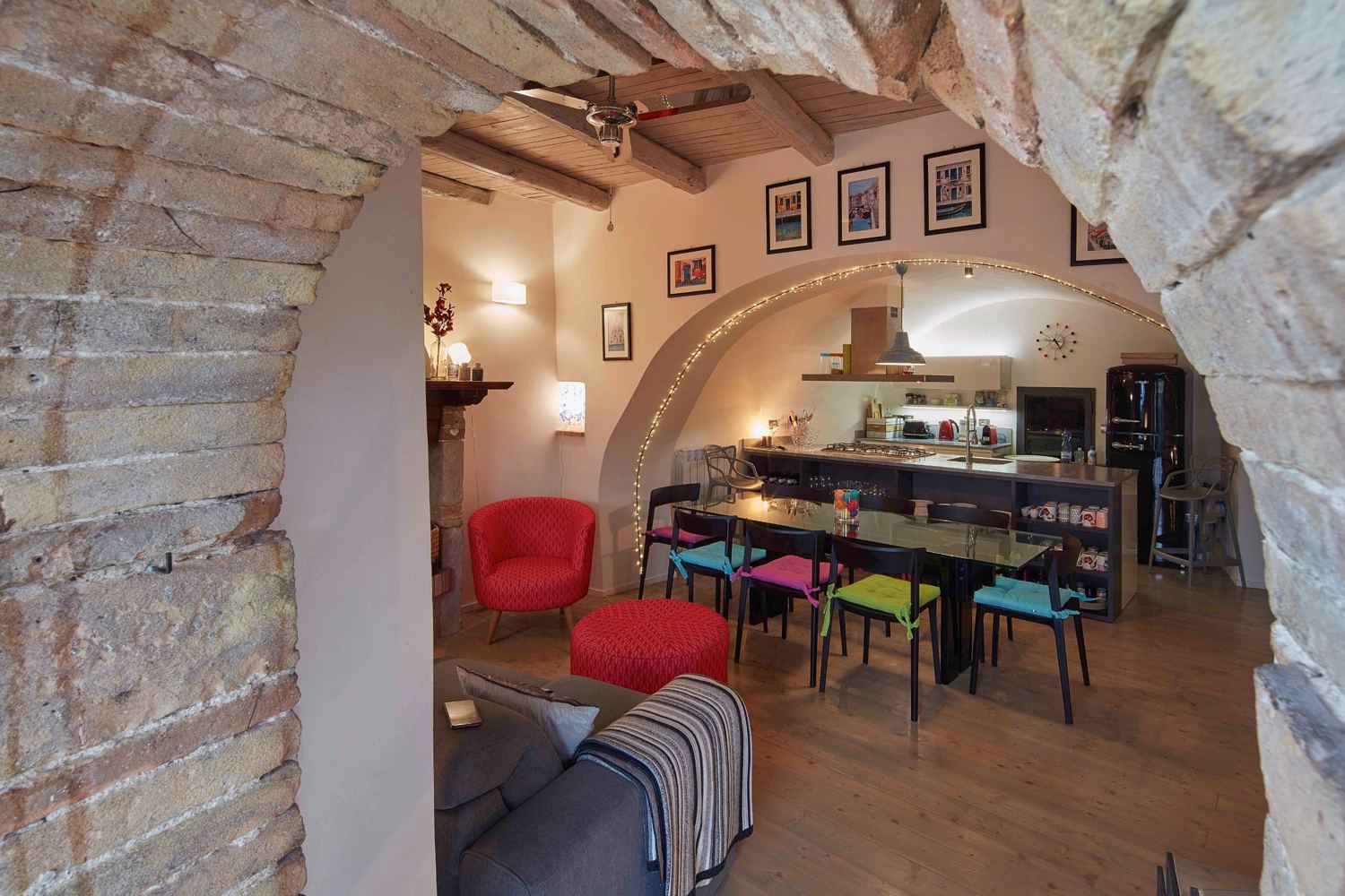 View through a rough stone arch into the dining room and kitchen